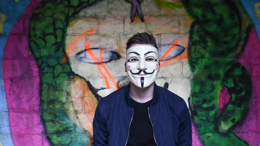Grafiti duvarı önünde yüzünde maske olan kişi