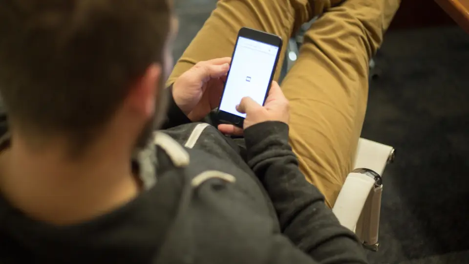 Oturduğu yerde akıllı telefon ekranına bakan adam