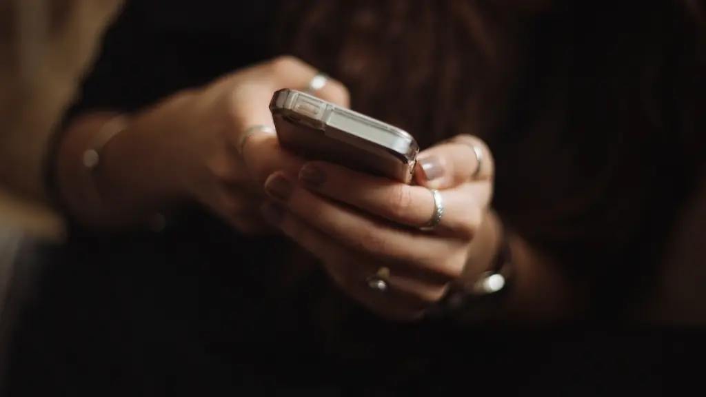 Loş ışıkta iki eliyle akıllı telefon kullanan kişi