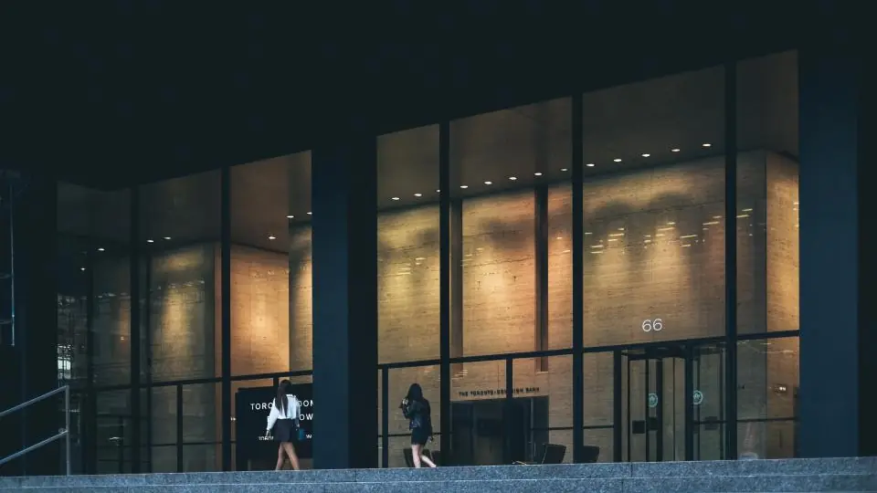 Akşam ışıkları yanan cam cepheli bir ofis binası girişi