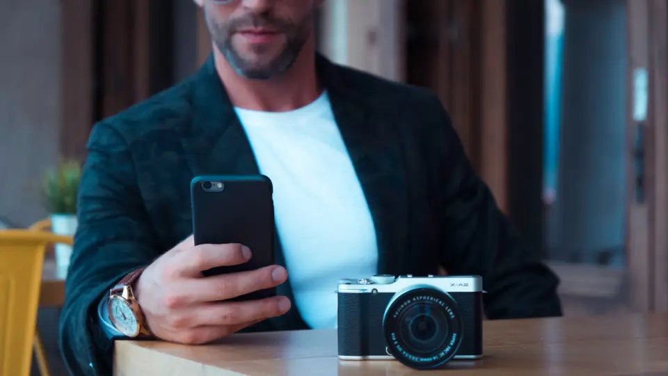 Masada fotoğraf makinesinin yanında telefonuna bakan adam