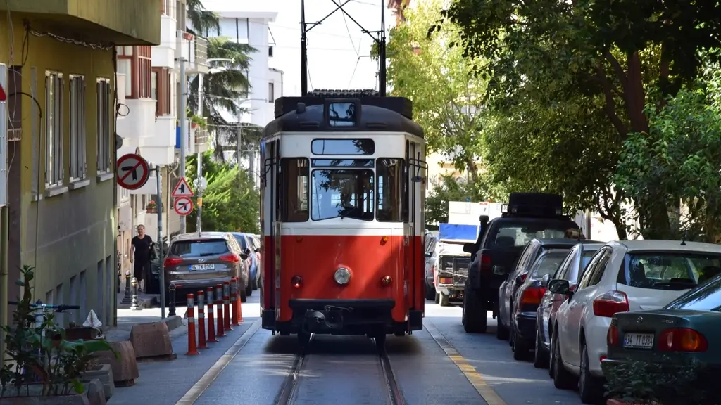 Ağaçlı bir sokakta ilerleyen kırmızı-beyaz nostaljik tramvay