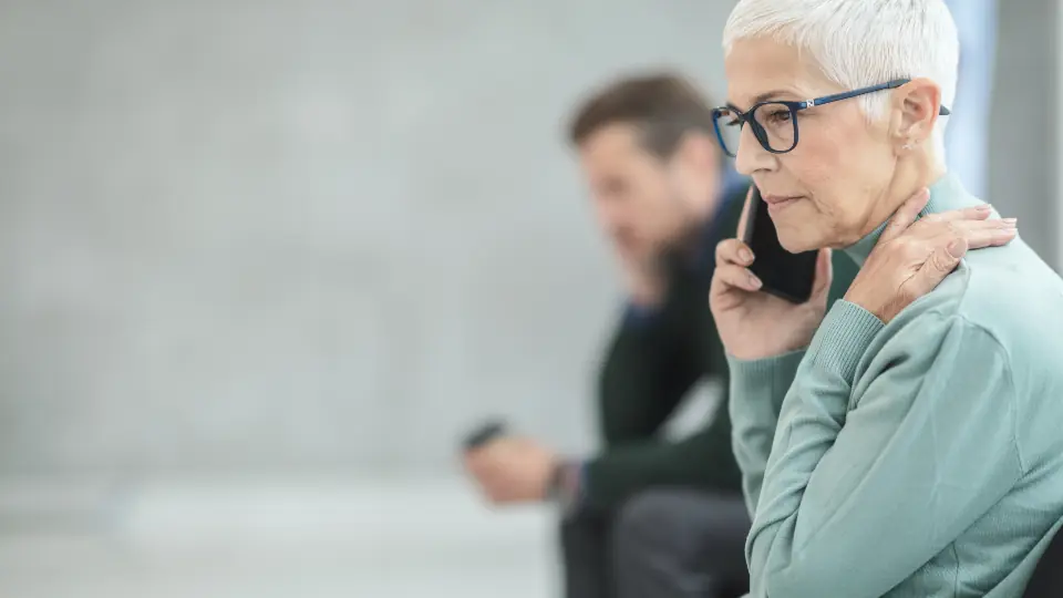 Telefonla konuşurken endişeli görünen kısa beyaz saçlı kadın